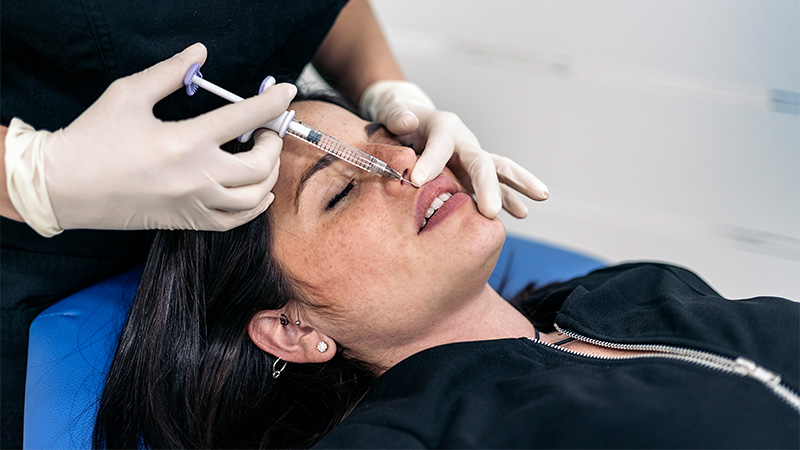 A young woman receiving a Botox/Dysport/Xeomin injection in the upper lip.