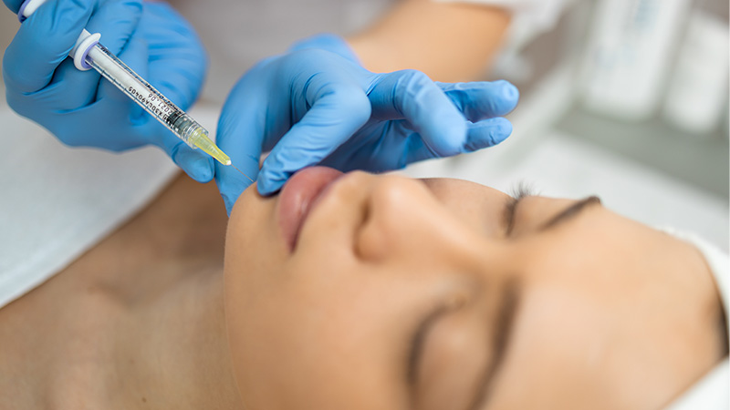 A woman recieving a Juvéderm injection in the chin.